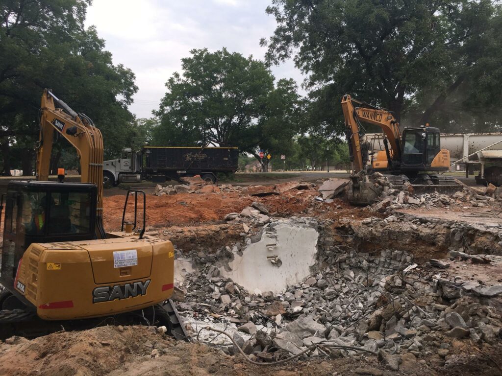 excavators demolishing a concrete pool