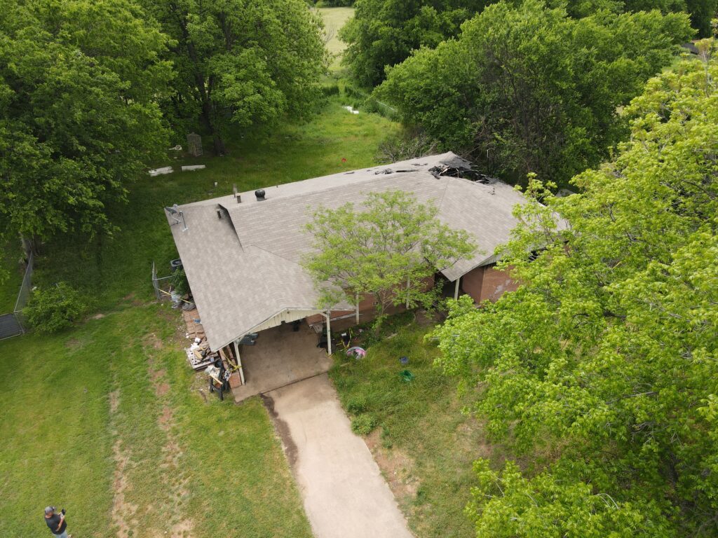 An aerial and distant view of a home in Granbury, Texas before it was demolished by Wannco Services demolition contractor that shows the damage caused by a house fire