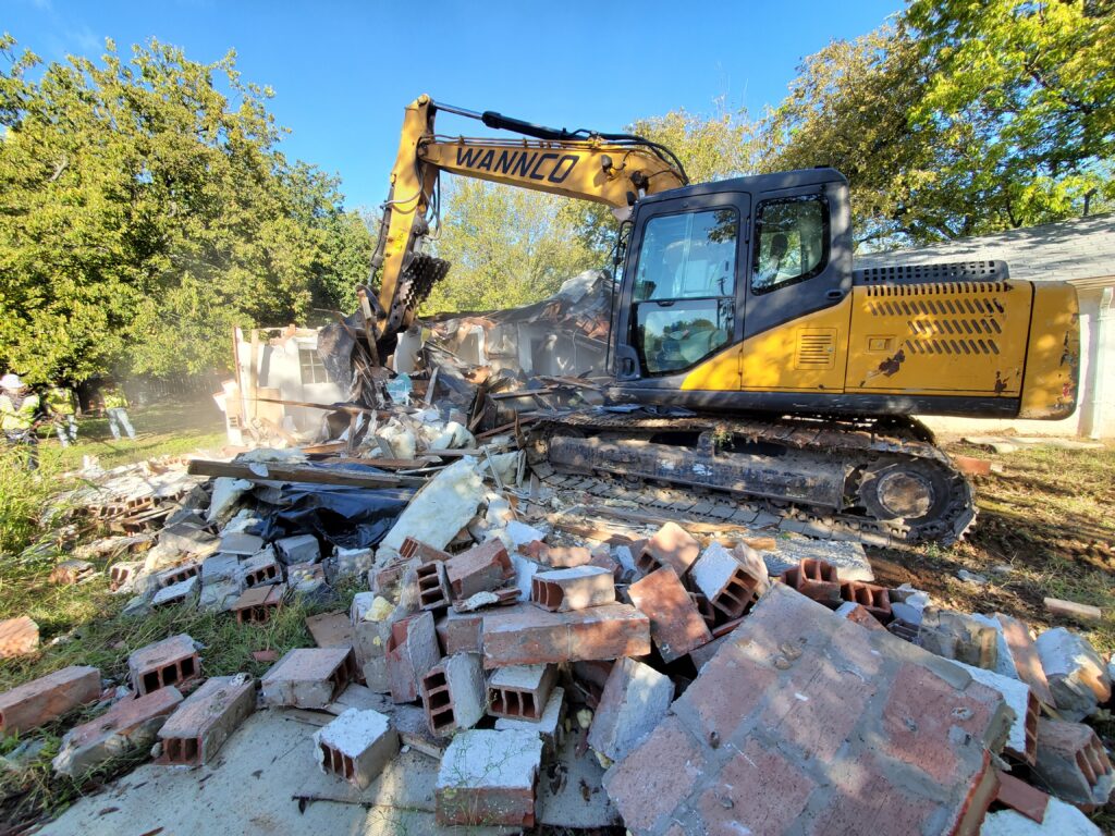 A Wannco Services excavator performing a demolition project on a concrete slab