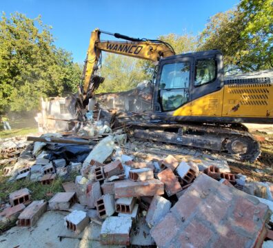 A Wannco Services excavator performing a demolition project on a concrete slab