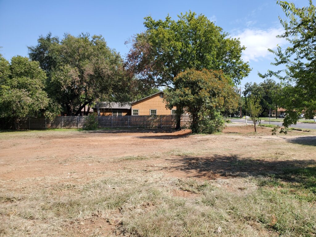 A lot after a demolition project cleared the land but left up from of the old vegetation and trees