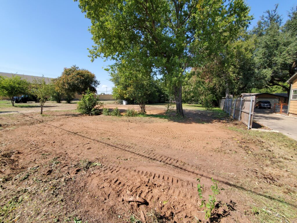 A lot after a demolition project cleared the land but left up from of the old vegetation and trees