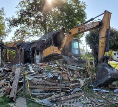 A Wannco Services excavator cleaning up a fire damaged home during a demolition project.