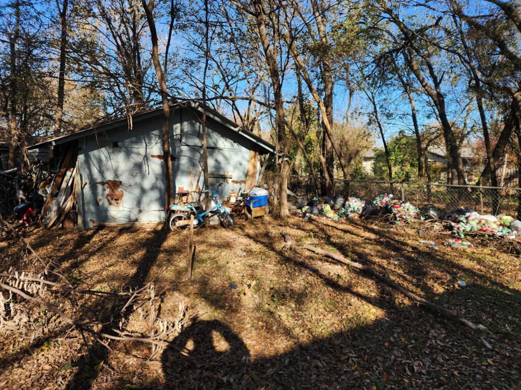 The side of a home with junk scattered everywhere in the yard due to hoarding in Glen Rose