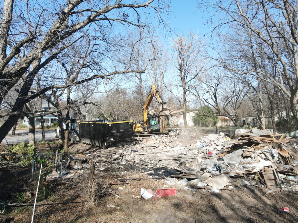 Side on view of a hoarders home in Glen Rose in the middle of a demolition company cleaning it up and tearing it down.