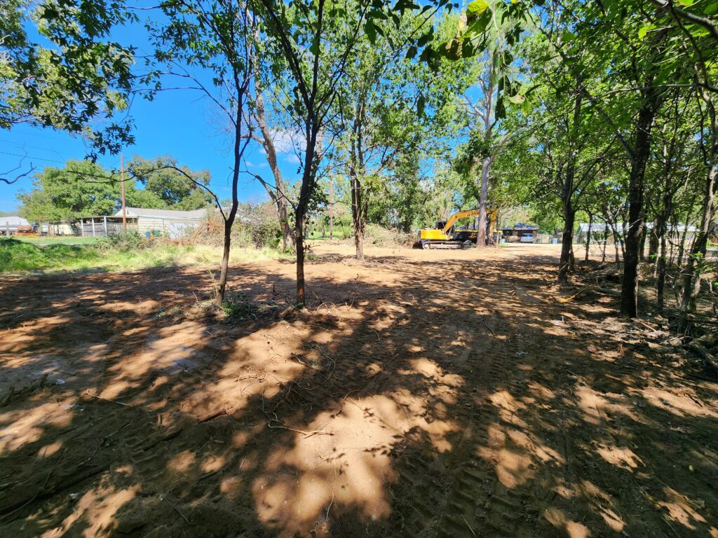 Cleared off parcel after a complete demolition project with an excavator in the background