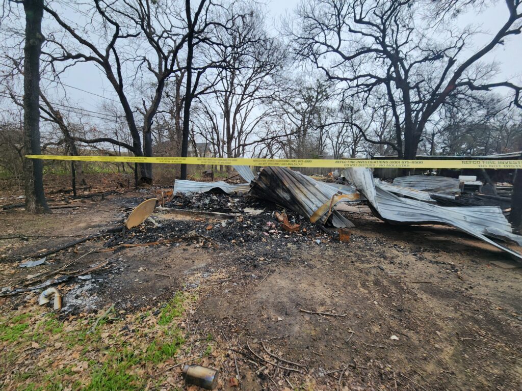View of fire damaged house in Granbury behind yellow caution tape
