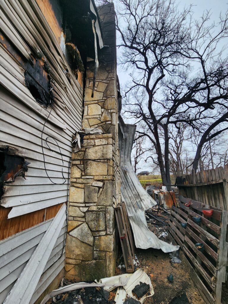 Side view of a house after it was damaged by a fire in Granbury. Shows the chimney