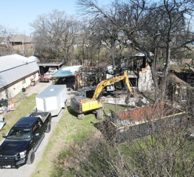Fire damaged home in Granbury with Wannco Services excavator and dumpster in front preparing for a full demolition